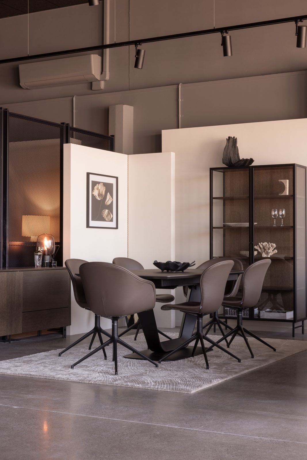 Esstisch mit sechs gepolsterten Drehstühlen, daneben eine Vitrine und ein Sideboard aus dunklem Holz